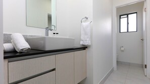 Een moderne badkamer met een ruime wastafel, een spiegel en een handdoekhouder.