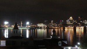 Un paisaje urbano nocturno con vista al río, edificios iluminados y un río tranquilo que refleja las luces.