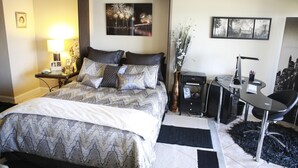 Un dormitorio ordenado con cama, mesita de noche, lámpara y escritorio con silla.