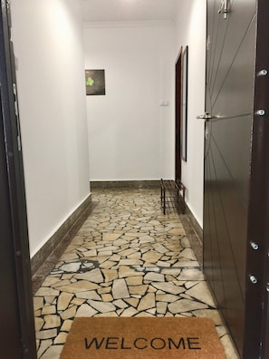 Enter a simple, functional hallway with a patterned floor and a welcoming entrance.
