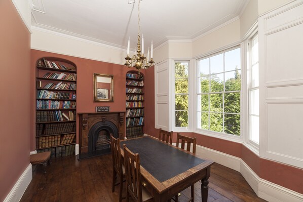 A library with bookshelves, a fireplace, and a large window.