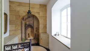 A room with a stone wall, a wooden cabinet, and a window with decorative items. - Georgian Manor With Panaromic Sea Views (Torquay, Devon)