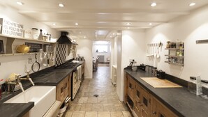 A modern kitchen with a central island, black countertops, and a variety of appliances and utensils. - Georgian Manor With Panaromic Sea Views (Torquay, Devon)