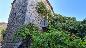 A stone tower with a narrow stone staircase leading up to a door. - Old Tower-House in Mani peninsula (LAGIA)