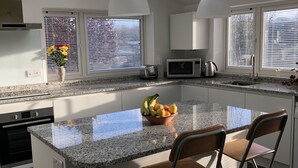 A modern kitchen with a central island, white cabinetry, a microwave, and a toaster. - COMFORTABLE, TRANQUIL, HOUSE ON RIVER TEIFI  LARGE GARDEN, CENTRAL, FREE PARKING (Cardigan)