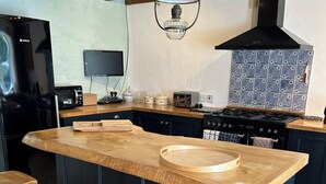 Una cocina con una isla central, taburetes de madera, una estufa y un salpicadero de azulejos.