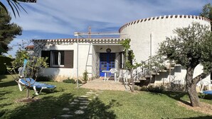 A house with a blue door, a small patio with chairs, and a stone pathway leading to the entrance. - Beautiful private villa for 7 people with A/C, WIFI, hot tub, TV and patio (Cambrils)