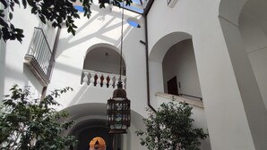 A narrow corridor with arches, a hanging lantern, and potted plants. - Henry House (Sorrento)