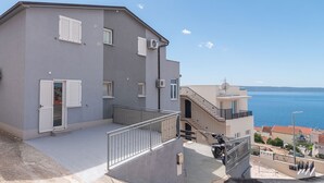 Ein mehrstöckiges Gebäude mit Balkonen, einer Treppe und Blick auf das Meer.