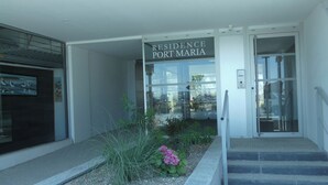 Una entrada moderna de edificio con un letrero que dice "Residence Port Maria".