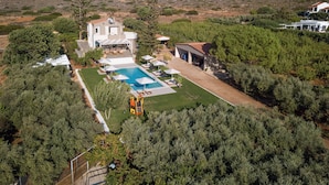 Una villa moderna con piscina, un porche cubierto y montañas al fondo.