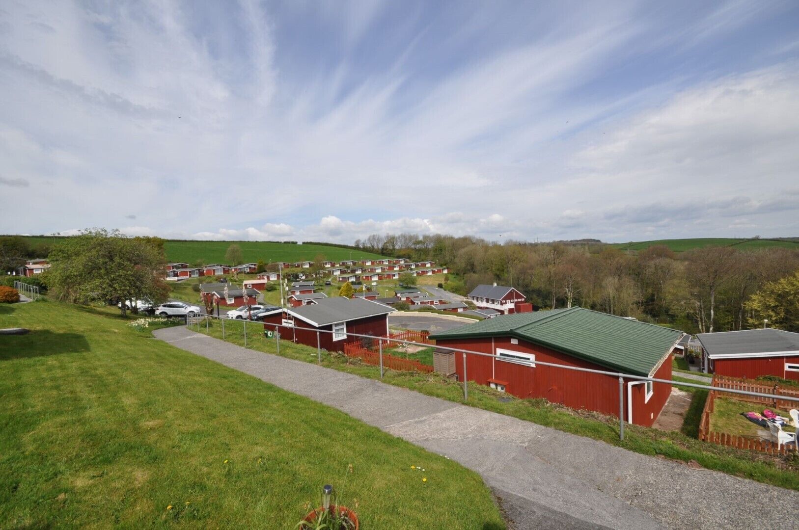 A residential area with red houses, a paved path, and green fields.