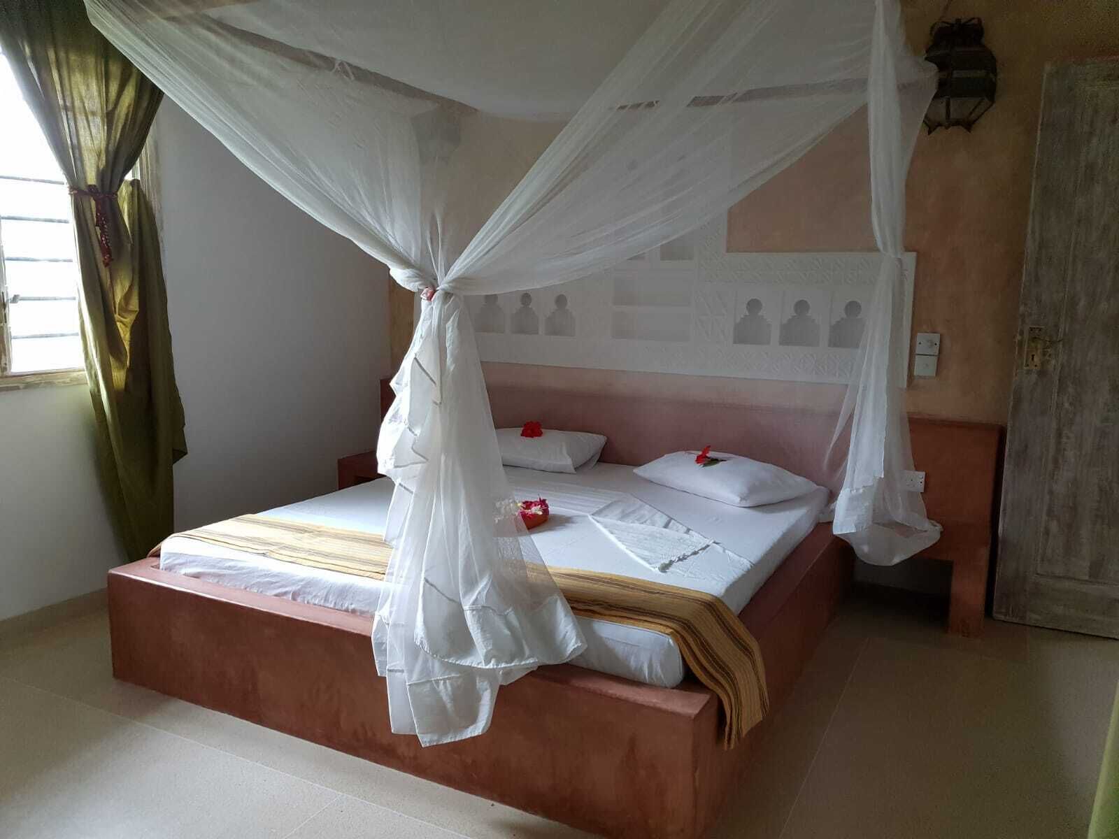 A bed with a canopy, a bedside table, and a wall with a patterned design.