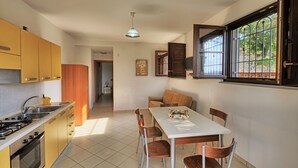 A compact kitchen with a dining area, a stove, and a window with bars. - Farmhouse with infinity pool: A unique experience-Onice (castellabate)