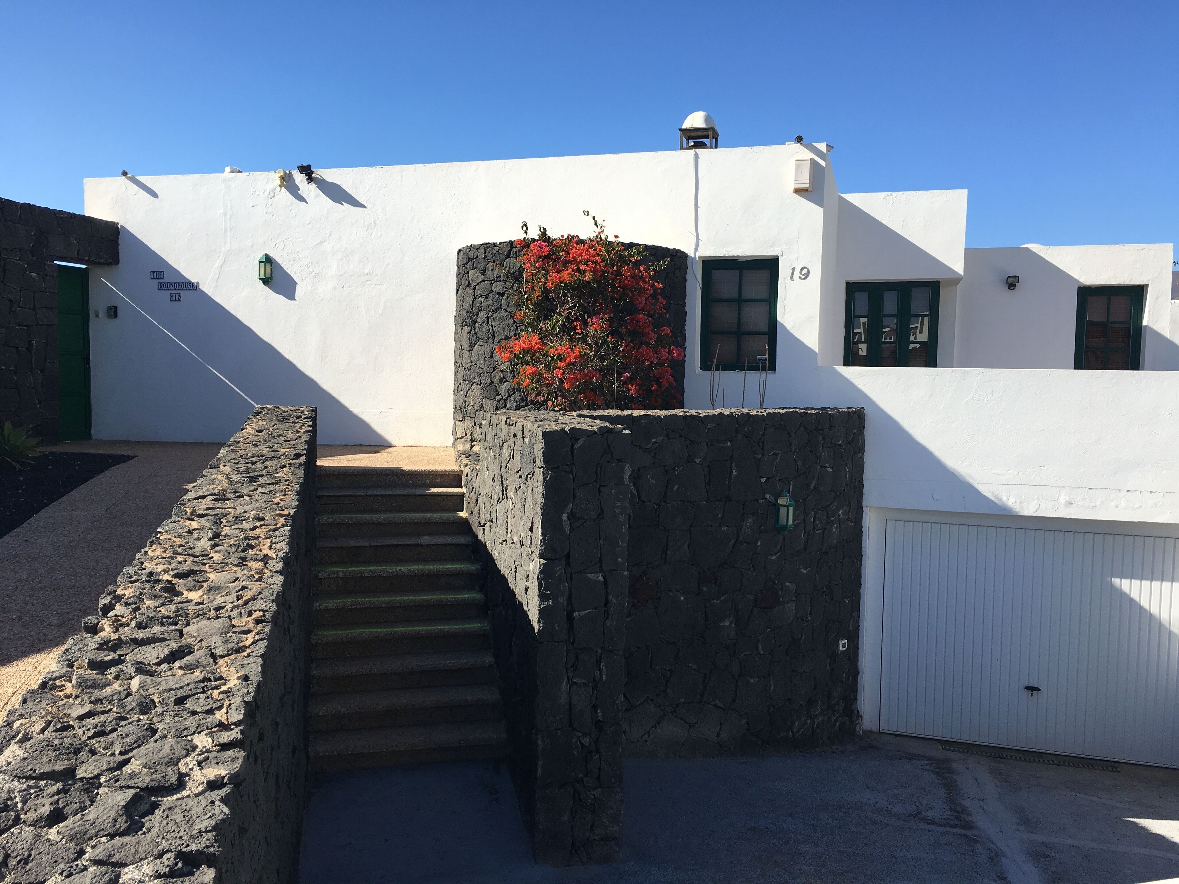 A white building with a stone staircase leading to a door marked "19".
