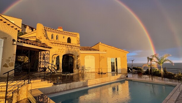 A pool area with a building featuring arched doorways and a stone facade. - AGAY - Charming villa with heated swimming pool and exceptional sea view (Saint-Raphaël)