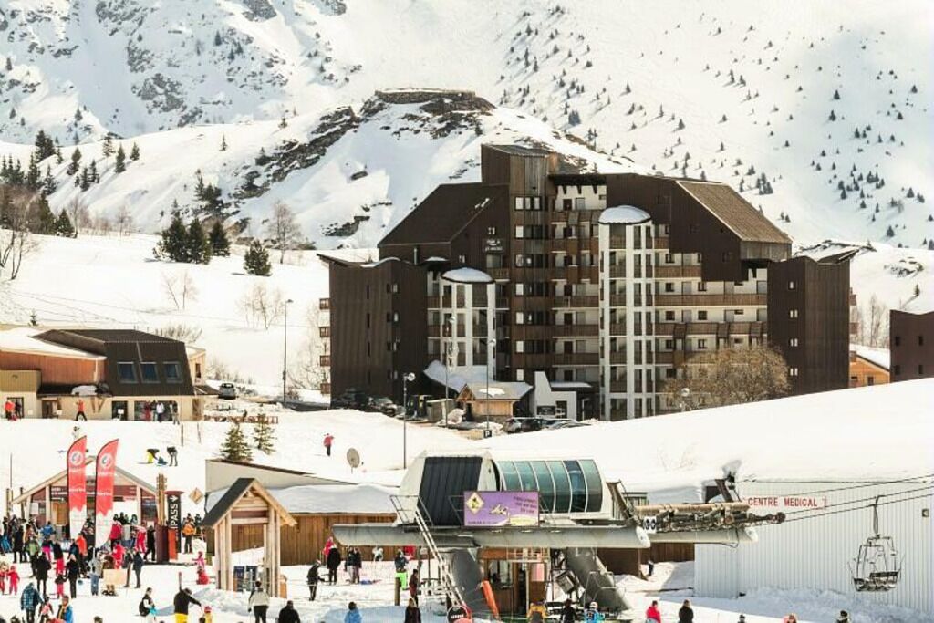 A ski resort with a large building, ski lifts, and a crowd of people.