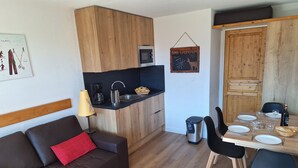 A compact living space with a kitchenette, a dining area, and a sofa with red cushions. - apartment/ flat - Alpe d'huez (Huez)