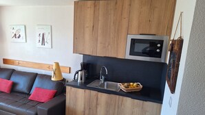 A modern kitchen with wooden cabinets, a black countertop, a microwave, and a coffee maker. - apartment/ flat - Alpe d'huez (Huez)