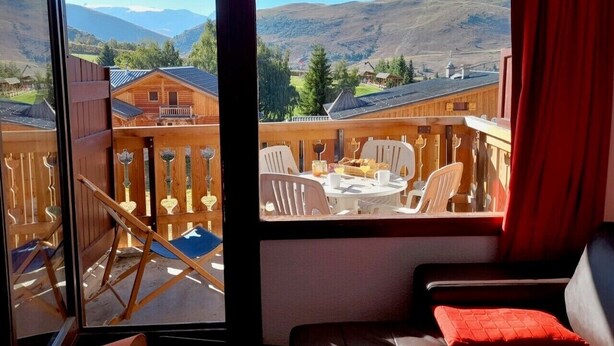 A balcony with a table and chairs, a wooden fence, and a view of mountains. - apartment/ flat - Alpe d'huez (Huez)