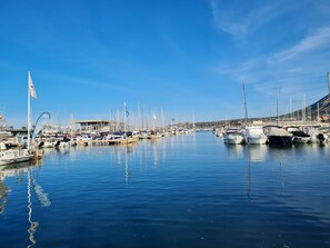 A marina with numerous boats docked, calm water, and a clear sky.
