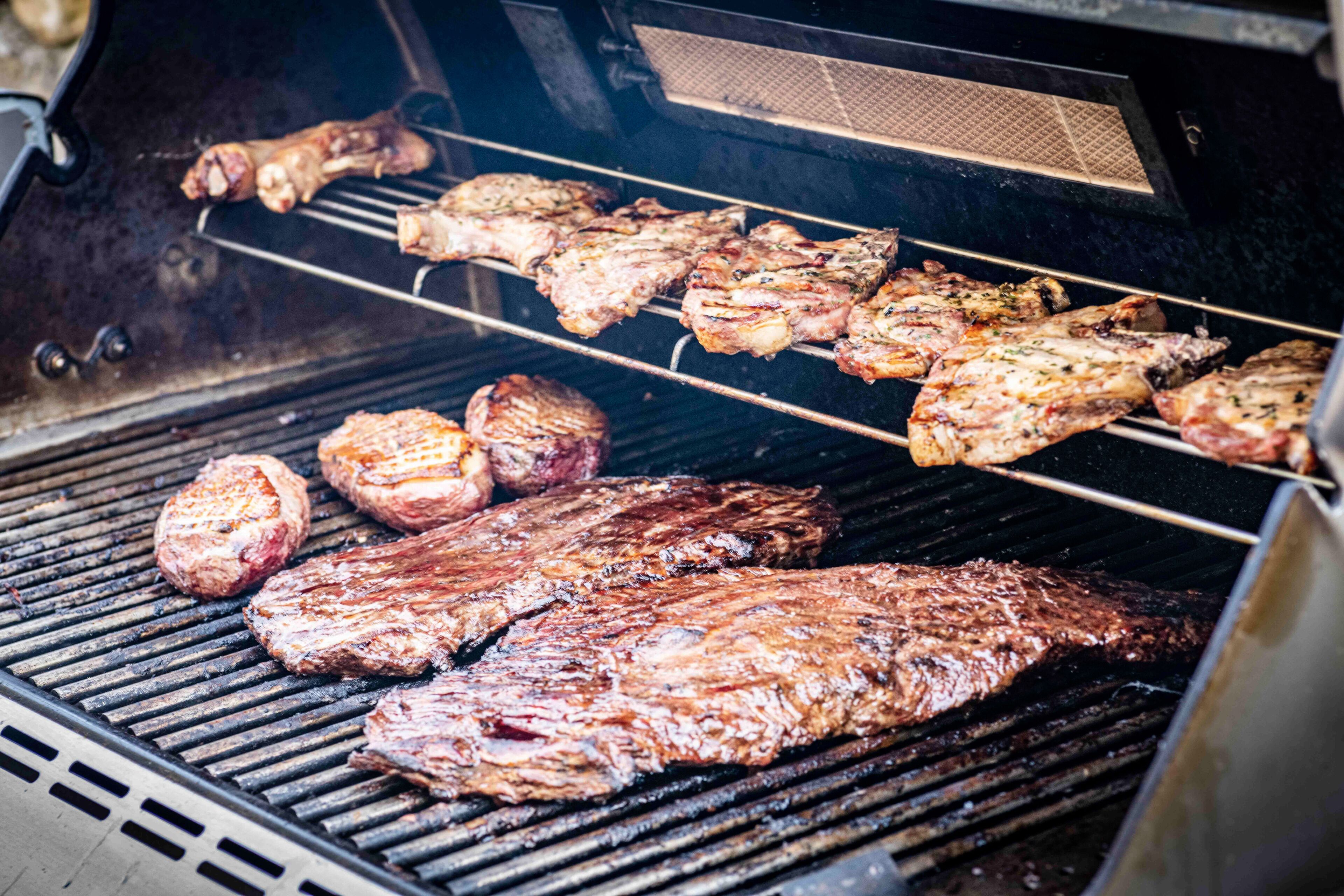 A grill with various meats being cooked.