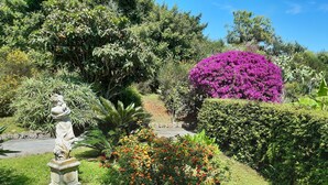 A garden with a statue, a variety of plants, and a purple flowering bush. - Lauretta apartment in elegant complex (Ceriale)