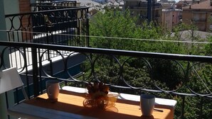 A balcony with a table and chairs, overlooking a cityscape and the sea. - Lauretta apartment in elegant complex (Ceriale)