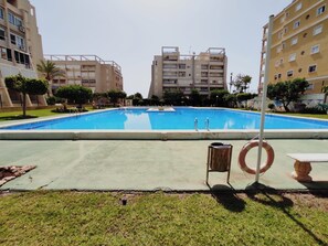 A swimming pool surrounded by apartment buildings, with a lifebuoy and a trash bin nearby. - Torrevieja, 360 days of sunshine to enjoy; spacious apartment, swimming pools and sea, Nl. (Torrevieja)