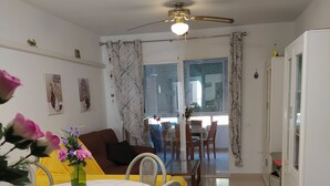 Una sala de estar con comedor, un sofá, una mesa con un florero y un ventilador de techo.