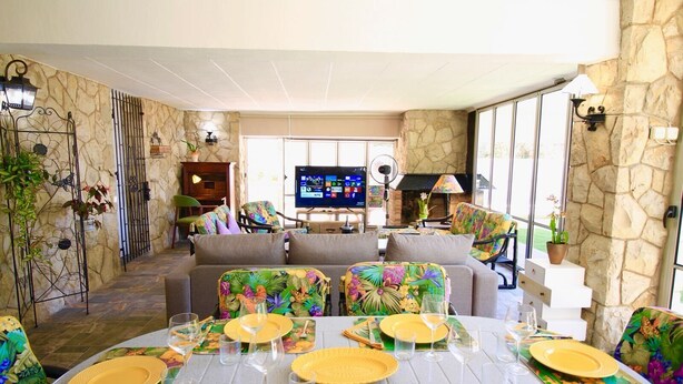 Uma sala de jantar com parede de pedra, uma TV e uma lareira.