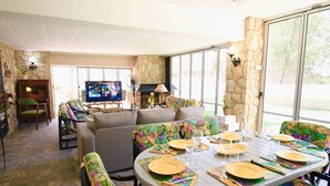 Uma sala de jantar com parede de pedra, uma televisão e uma lareira.