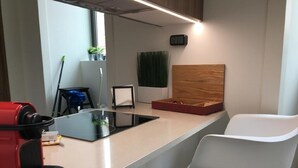 Una cocina moderna con encimera negra, un electrodoméstico rojo y una silla blanca.