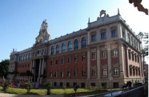 Stately building with a classical facade, featuring a central entrance and arched windows.