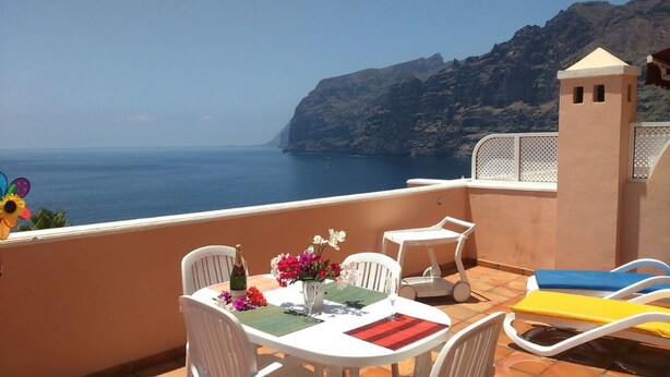 A terrace with a table set for two, overlooking a coastal view. - APARTMENT WITH SEA VIEWS AND FANTASTIC SUNSHINE (Santiago del Teide)