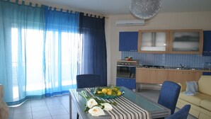 Una cocina moderna con armarios azules, una estufa y un horno. Hay una mesa de comedor con cubierta de vidrio y un cuenco con fruta.
