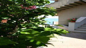 Un balcón con vista al mar, una planta en maceta y una escalera.