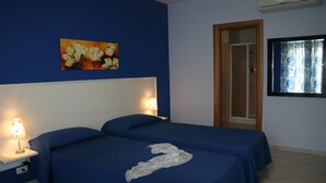 Una habitación de hotel con dos camas, un cuadro en la pared, una puerta y una ventana con cortinas.