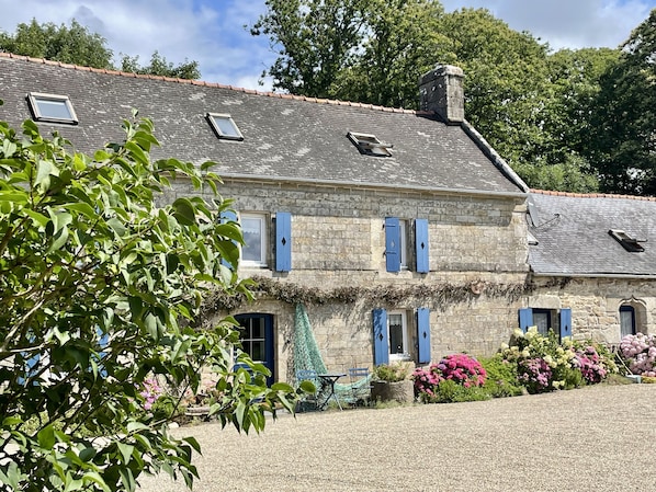 Un bâtiment en pierre doté de nombreuses fenêtres et une allée gravillonnée.