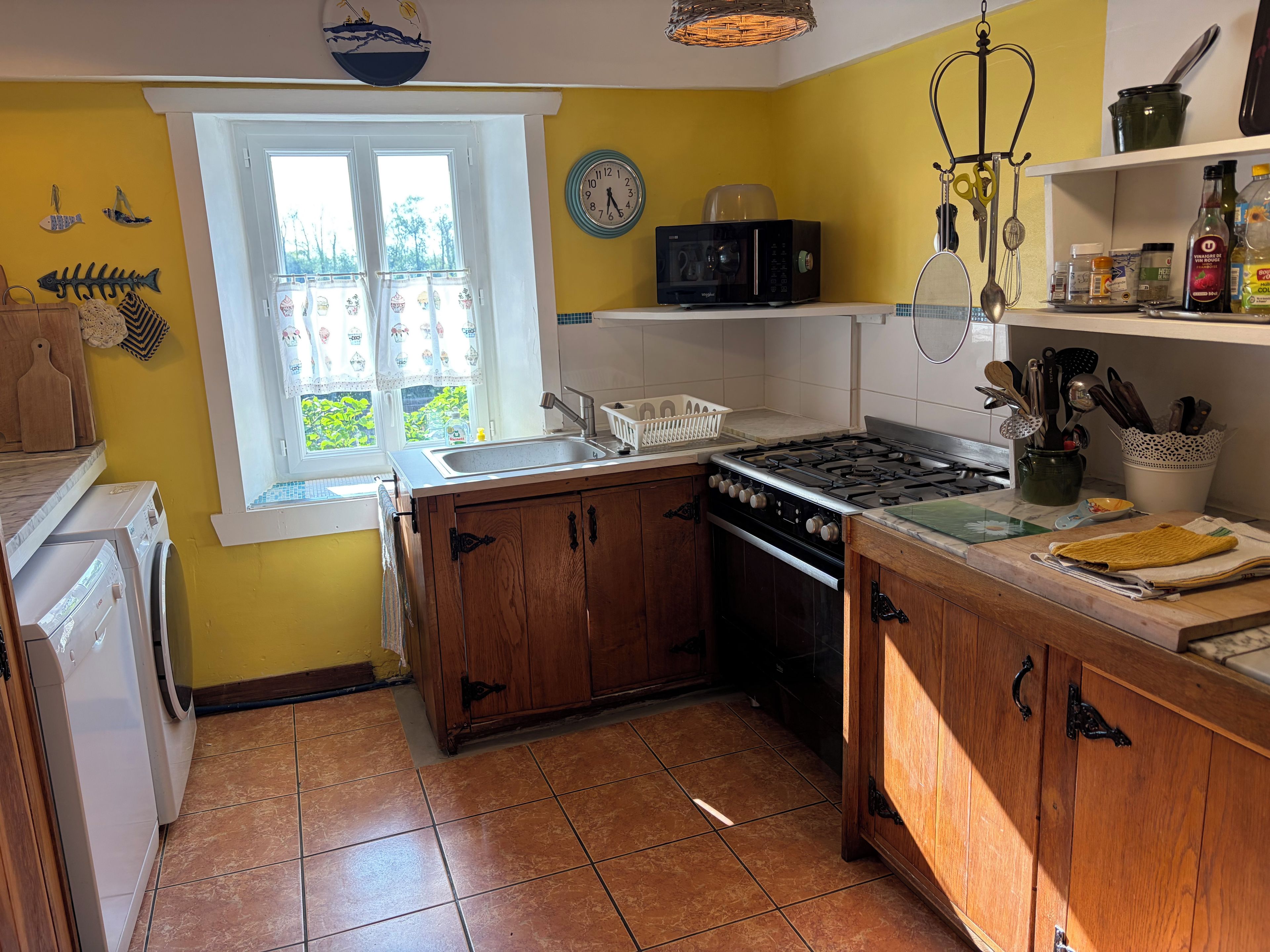 Una cocina con estufa, pileta y diferentes utensilios.