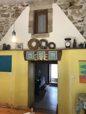 Ein rustikaler Innenraum mit einer Steinwand, einer Holzbalkendecke und einer gelben Wand mit einem 'ETE'-Schild.