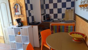 A compact kitchen with a checkered backsplash, a coffee maker, and a colorful tablecloth.