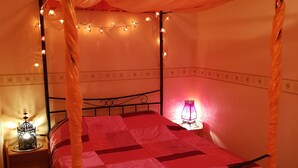 A four-poster bed with a canopy, two bedside lamps, and a decorative lantern on a wooden nightstand.