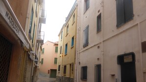Une rue étroite bordée d’immeubles dotés de balcons et de volets.