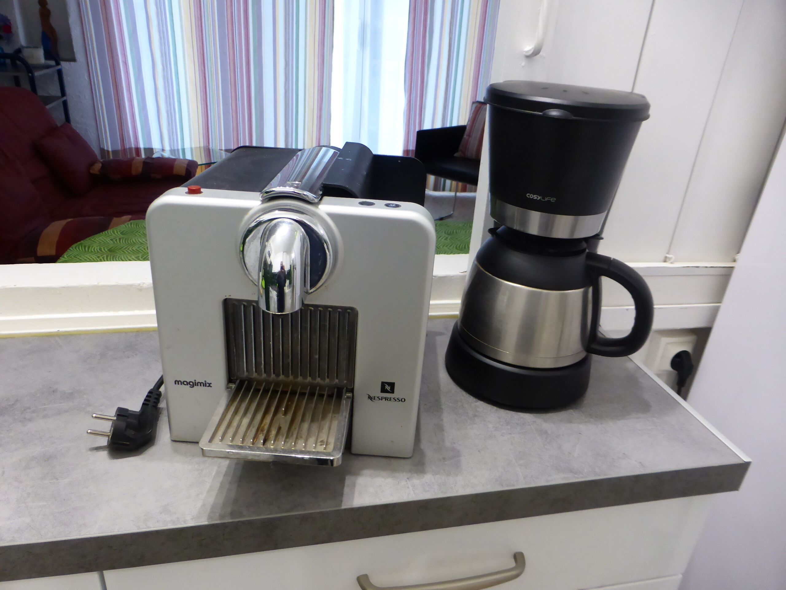 Eine Kaffeemaschine mit Wasserbehälter und Tropfschale auf einer Küchenarbeitsplatte.