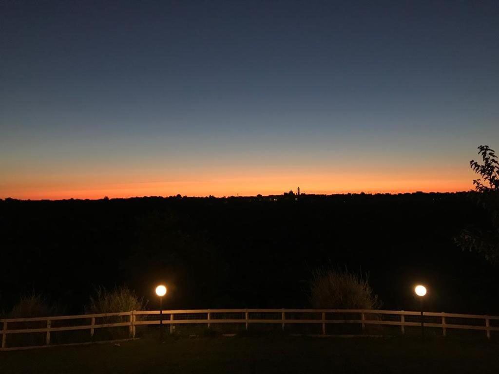 Ein Sonnenuntergang über einer ländlichen Landschaft, im Vordergrund ein Holzzaun.
