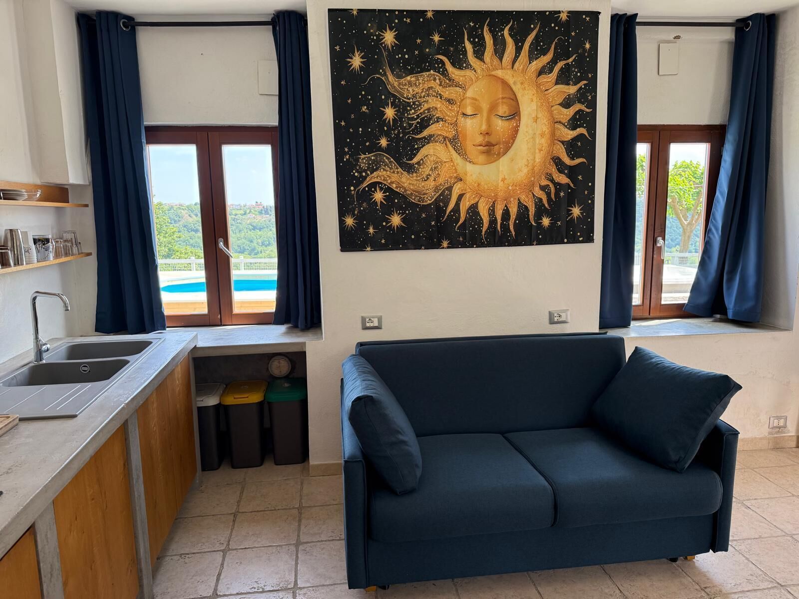 Een woonkamer met een bank, een wastafel en uitzicht op een zwembad.