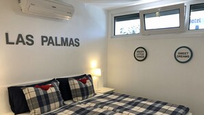 Hotellihuone, jossa on sänky, seinään asennettu ilmastointilaite ja kaksi pyöreää seinäkoristetta.