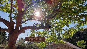 A rustic stone building with a wooden door, surrounded by greenery and a 'Welcome' sign hanging from a tree. - For Nature Lovers ... (Saint-André-D'olérargues)