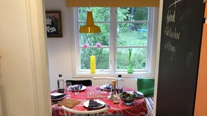 A dining area with a table set for four, a window with a view of greenery, and a chalkboard with text. - Beachfront classic summer cottage for the family in Ahus. Ideal for families with children (Åhus)